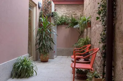 two red chairs sitting on a patio with plants at HOMEinTOWN Almada - Downtown Elegant Apartment - Terrace AC & WIFI in Porto