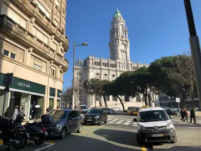 a busy city street with a large building with a clock tower at HOMEinTOWN Almada - Downtown Elegant Apartment - Terrace AC & WIFI in Porto