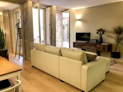 a living room with a white couch and a tv at HOMEinTOWN Almada - Downtown Elegant Apartment - Terrace AC & WIFI in Porto