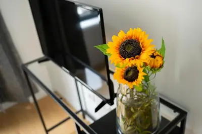 a vase filled with sunflowers sitting on a glass table at Oporto Bonjardim Residence in Porto