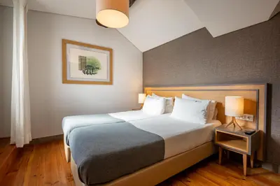 a hotel room with a large bed and two lamps at Santa Catarina FLH Suites in Porto