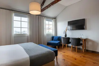 a hotel room with a bed and a table and chairs at Santa Catarina FLH Suites in Porto