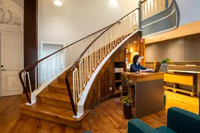 a woman sitting at a desk under a staircase at Santa Catarina FLH Suites in Porto