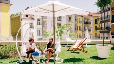 two women sitting in chairs under an umbrella at InterContinental Porto - Palacio das Cardosas by IHG in Porto