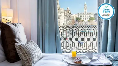 a table with a plate of food on a bed with a window at InterContinental Porto - Palacio das Cardosas by IHG in Porto