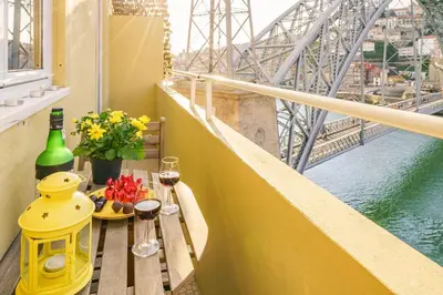a balcony with a table with wine glasses and a bridge at BestVillas Casa do Rio in Vila Nova de Gaia