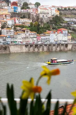 a boat on a river with buildings in the background at BestVillas Casa do Rio in Vila Nova de Gaia