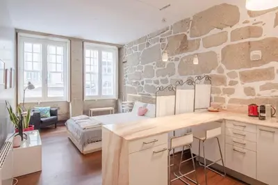 a kitchen and living room with a stone wall at OHH - Ganesha studio- Oporto Center in Porto