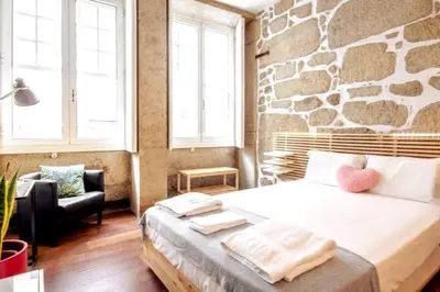 a bedroom with a bed and a stone wall at OHH - Ganesha studio- Oporto Center in Porto