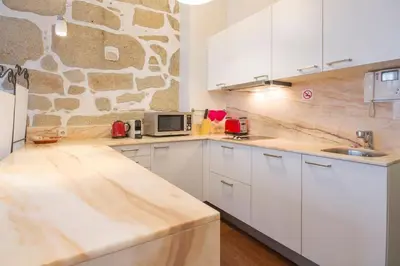 a kitchen with white cabinets and a stone wall at OHH - Ganesha studio- Oporto Center in Porto
