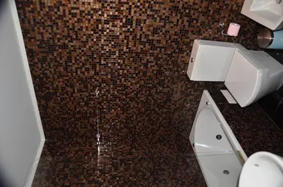 a bathroom with a toilet and a brown tiled floor at PATH Dukes Apartment in Porto