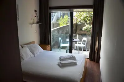 a bedroom with a bed and a balcony with a table at PATH Dukes Apartment in Porto