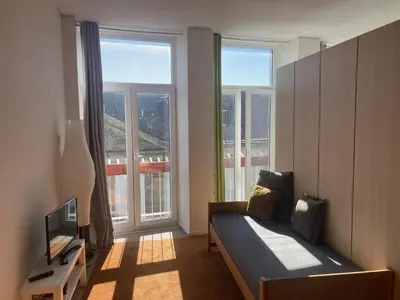 a living room with a couch and a tv and windows at PATH Biblioteca Apartment in Porto
