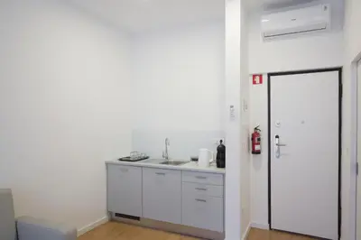 a white kitchen with a sink and a door at Porto Bonjardim Apartments in Porto