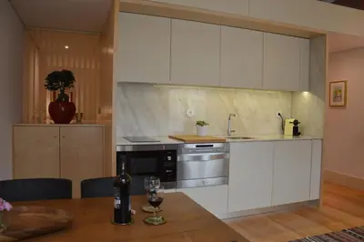 a kitchen with white cabinets and a table with a bottle of wine at Oporto Like Home IV - Mezzanine in Porto