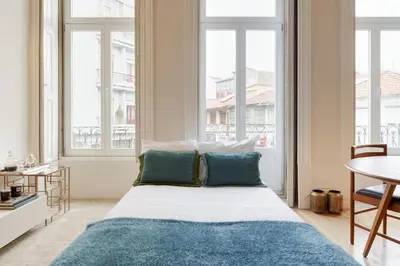 a bedroom with a bed with a blue rug and windows at Visconde Mezzanine in Porto