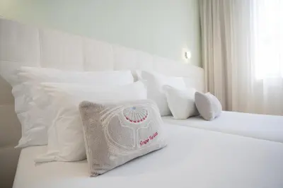 a white bed with white pillows and a pillow on it at Turista Da Trindade in Porto