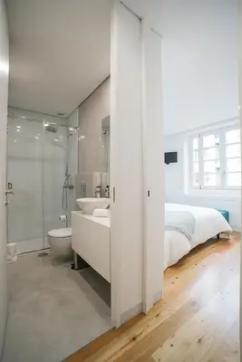 a white bedroom with a bed and a tub and a sink at D'Autor Apartments Sá da Bandeira in Porto