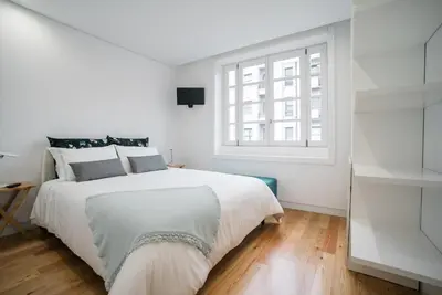 a white bedroom with a large bed and a window at D'Autor Apartments Sá da Bandeira in Porto