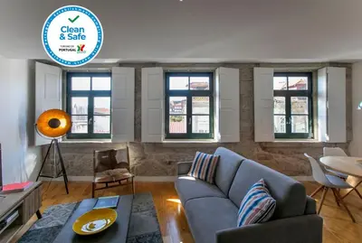 a living room with a couch and a table and windows at Modern 18th Century Flat in Porto