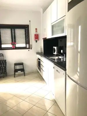 a kitchen with white cabinets and a black counter top at Cocooning Appartement in Porto