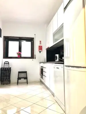 a white kitchen with a refrigerator and a window at Cocooning Appartement in Porto