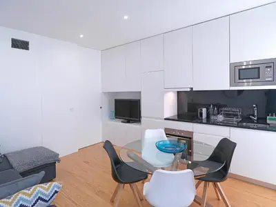 a kitchen with white cabinets and a table and chairs at FLH Porto Balcony Apartment in Porto