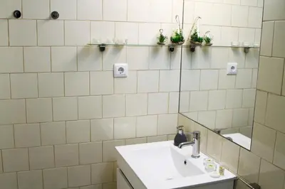 a white tiled bathroom with a sink and mirror at Porto Feeling in Porto