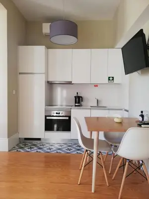 a kitchen with white cabinets and a wooden table at Mercado dos Poetas – Tourism Apartments in Porto