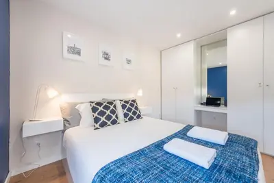 a white bedroom with a large bed and a window at GuestReady - Theater Apartment in Porto