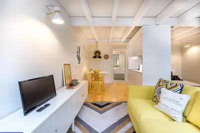 a living room with a yellow couch and a tv at Studio Tomás Gonzaga in Porto