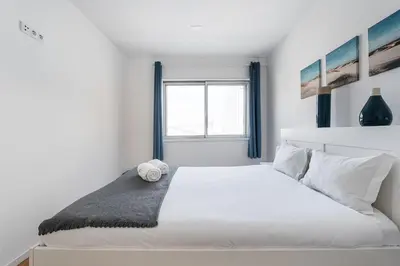 a white bedroom with a large bed with a window at GuestReady - Beautiful Plateau in Porto