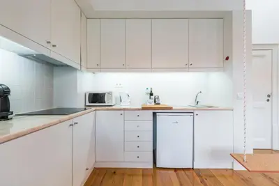 a white kitchen with white cabinets and a microwave at GuestReady - Charming Studio in Porto! in Porto