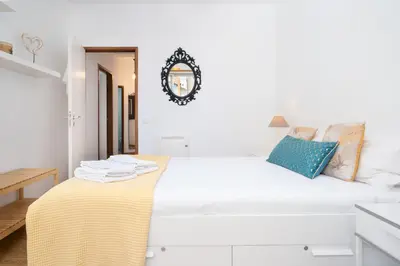 a white bedroom with a bed with a yellow blanket on it at Renovated 3BR Apt Near City Hotspots with Great Value in Porto