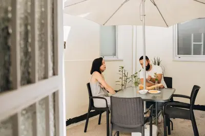 a man and a woman sitting at a table under an umbrella at Cozy 1-Bedroom with Private Terrace in Palmela in Porto