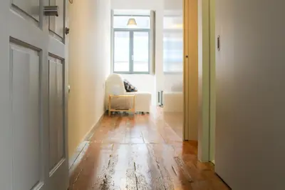 a hallway with a white chair and a window at Bonjardim Flats - T1 in Porto