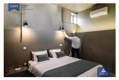 a man is standing next to a bed in a room at ORM - Almada Terrace Apartment in Porto