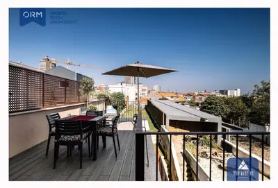 a balcony with a table and chairs and an umbrella at ORM - Almada Terrace Apartment in Porto