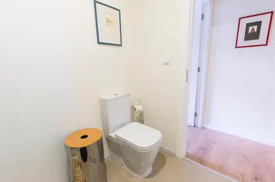 a bathroom with a white toilet and a wooden stool at Opo Arte Apartment with terrace and A/C in Porto