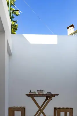 a table with two stools in front of a white wall at Vale71house in Porto