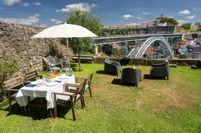 a table with an umbrella and chairs and a bridge at Manor House Porto in Porto