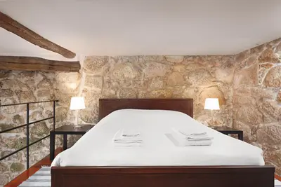 a bedroom with a bed and a stone wall at Manor House Porto in Porto
