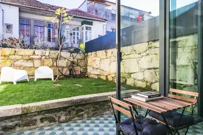 a patio with a wooden table and chairs and a yard at Visconde Garden in Porto