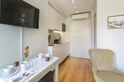 a small white kitchen with a table and a chair at Charming City Centre Studio near Aliados - Inside Porto Apartments 