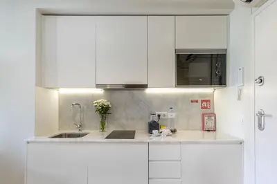 a kitchen with white cabinets and a sink at Charming City Centre Studio near Aliados - Inside Porto Apartments 