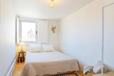 a white bedroom with a bed and a window at Own Places Cedofeita Apartments in Porto