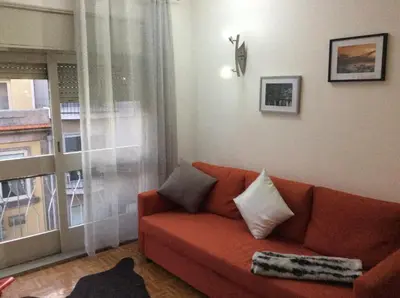 a living room with a red couch and a window at Downtown Sunny Apartment in Porto
