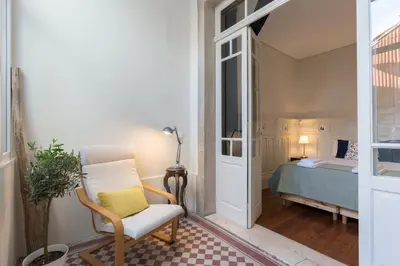 a living room with a chair and a bedroom at APorTo - 2 Suites in Porto