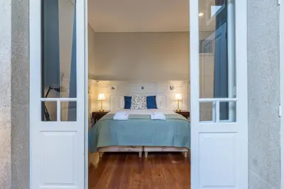 a bedroom with a bed with blue sheets and two lamps at APorTo - 2 Suites in Porto