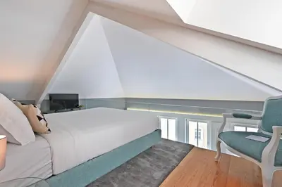 a bedroom with a white bed and a blue chair at Villa Mouzinho by ON Apartments in Porto
